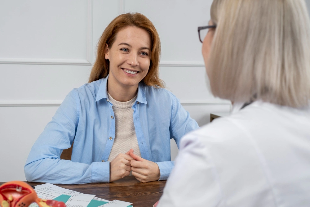 mujer sonriente en consulta con doctora de espaldas